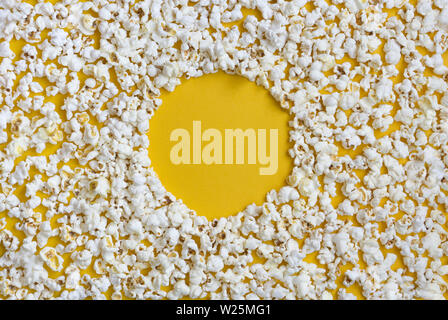 Grenze von Popcorn über Gelb Hintergrund mit Kopie Raum verstreut, Ansicht von oben. Minimalistisches Design für Film Poster, Unterhaltung Konzept. Nahaufnahme der