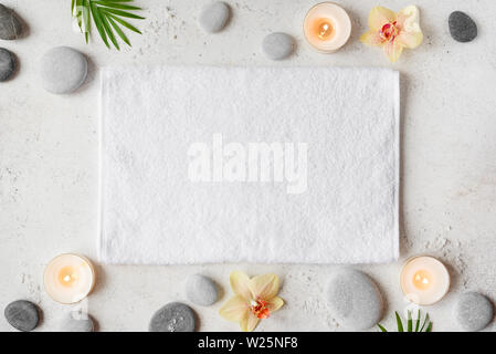 Spa-Konzept auf weißem Stein, Palm Blätter, Blumen, Kerzen und zen wie Graue Steine, Ansicht von oben, kopieren. Stockfoto