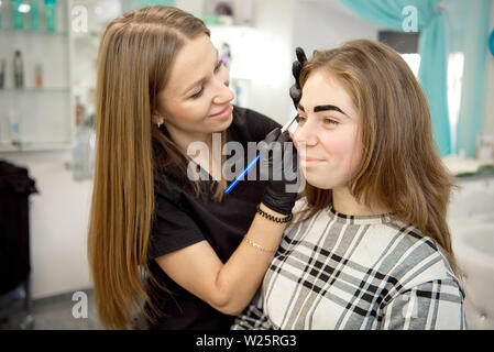 Make-up-Artist, professionelle Make-up einer jungen Frau in der Nähe des Spiegels in Beauty Studio. Stockfoto