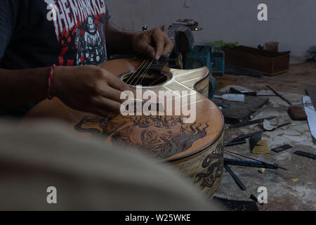 GIANYAR, Bali/Indonesien - 30. MAI 2019: Eine klassische Gitarre Handwerker ist die Paarung Gitarre Saiten seiner Gitarre. Er paßte auch die Gitarre Ton am Git Stockfoto