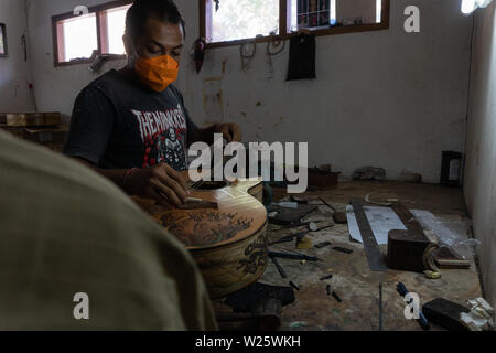 GIANYAR, Bali/Indonesien - 30. MAI 2019: Eine klassische Gitarre Handwerker ist die Paarung Gitarre Saiten seiner Gitarre. Er paßte auch die Gitarre Ton am Git Stockfoto