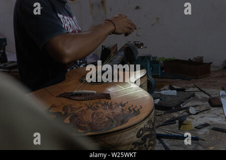 GIANYAR, Bali/Indonesien - 30. MAI 2019: Eine klassische Gitarre Handwerker ist die Paarung Gitarre Saiten seiner Gitarre. Er paßte auch die Gitarre Ton am Git Stockfoto