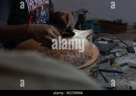 GIANYAR, Bali/Indonesien - 30. MAI 2019: Eine klassische Gitarre Handwerker ist die Paarung Gitarre Saiten seiner Gitarre. Er paßte auch die Gitarre Ton am Git Stockfoto