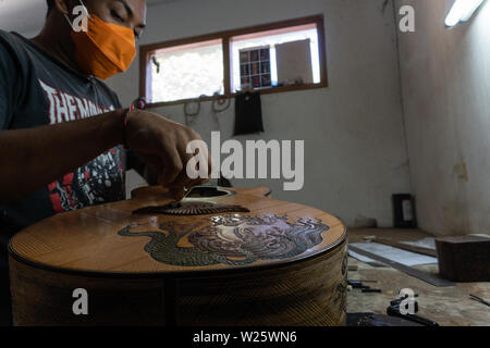 GIANYAR, Bali/Indonesien - 30. MAI 2019: Eine klassische Gitarre Handwerker ist die Paarung Gitarre Saiten seiner Gitarre. Er paßte auch die Gitarre Ton am Git Stockfoto