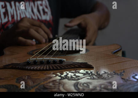 GIANYAR, Bali/Indonesien - 30. MAI 2019: Eine klassische Gitarre Handwerker ist die Paarung Gitarre Saiten seiner Gitarre. Er paßte auch die Gitarre Ton am Git Stockfoto