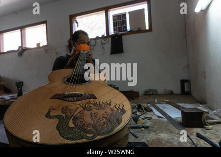 GIANYAR, Bali/Indonesien - 30. MAI 2019: Eine klassische Gitarre Handwerker ist die Paarung Gitarre Saiten seiner Gitarre. Er paßte auch die Gitarre Ton am Git Stockfoto