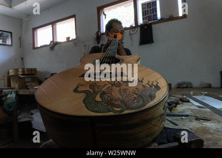 GIANYAR, Bali/Indonesien - 30. MAI 2019: Eine klassische Gitarre Handwerker ist die Paarung Gitarre Saiten seiner Gitarre. Er paßte auch die Gitarre Ton am Git Stockfoto