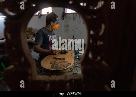 GIANYAR, Bali/Indonesien - 30. MAI 2019: Eine klassische Gitarre Handwerker ist die Paarung Gitarre Saiten seiner Gitarre. Er paßte auch die Gitarre Ton am Git Stockfoto