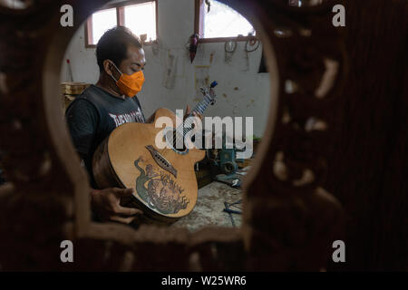 GIANYAR, Bali/Indonesien - 30. MAI 2019: Eine klassische Gitarre Handwerker ist die Paarung Gitarre Saiten seiner Gitarre. Er paßte auch die Gitarre Ton am Git Stockfoto