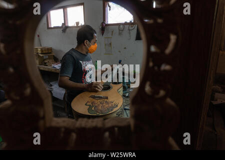 GIANYAR, Bali/Indonesien - 30. MAI 2019: Eine klassische Gitarre Handwerker ist die Paarung Gitarre Saiten seiner Gitarre. Er paßte auch die Gitarre Ton am Git Stockfoto