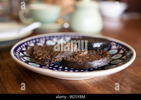 Traditionellen schottischen Haggis sind für Frühstück auf einer Hand serviert lackiert Platte mit einem unscharfen Hintergrund Stockfoto