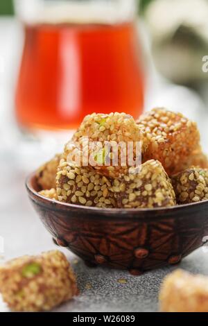 Traditionelle türkische begeistern. lokum. Orientalische Süßigkeiten mit Sesam und Pistazien in einer Keramik Schüssel auf dem Tisch. Ein Leckerbissen für Tee. Selektiver Fokus Stockfoto