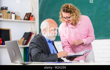 Schüler, Lehrer über Aufgabe. Lehrer und Schüler auf der Suche nach Buch. Schwierig zu erklären. Lösen von mathematischen Aufgaben. Buchen Sie Quelle wissen. School Buch Konzept. Helfen Sie mir bitte. Hausaufgaben prüfen. Stockfoto