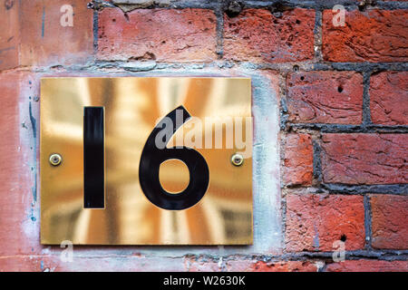 Haus Nummer 16 mit 16 auf einem Bronze Metall Plakette auf ein Red brick wall mit der Reflexion, wie die Union Jack, die Britische Flagge Stockfoto