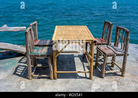 Bambus Tisch und Stühle aus Holz in leeren Cafe neben Meer Wasser in tropischen Strand. Close Up. Insel Koh Phangan, Thailand Stockfoto