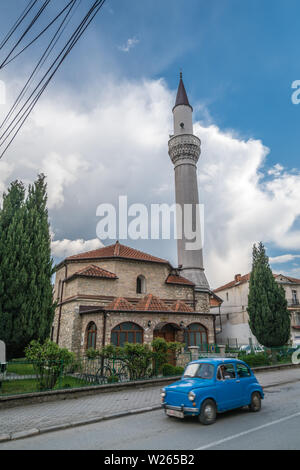 Ohrid, Mazedonien - April 2019: Winzige alte blaue Auto vor der Moschee Minarett in Ohrid, Mazedonien fahren Stockfoto