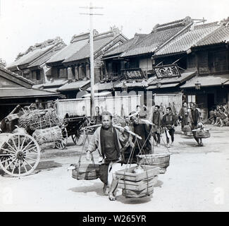 [1890s Japan - Nihonbashi Fischmarkt] - Männer Eimer mit Fisch auf dem Fischmarkt in Nihonbashi, Tokyo 1896 (Meiji 29). Der Markt wurde zerstört durch die Kanto Erdbeben (Kanto Daishinsai) September 1, 1923 (taisho 12). Es re-in Tsukiji 1935 eröffnet (Showa 10), wo es blieb bis zum 6. Oktober 2018 (Heisei 30). 20. Jahrhundert vintage Glas schieben. Stockfoto