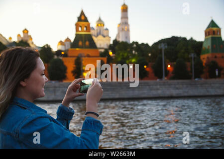 Frau touristische Bilder aufnehmen auf Handy während der Bootsfahrt auf dem Fluss Moskwa auf dem Hintergrund der Kreml. Reisen nach Russland Konzept. Stockfoto