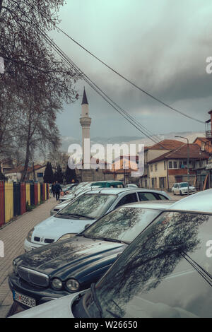 Ohrid, Mazedonien - April 2019: Reihe von privaten Autos vor Moschee Minarett in Ohrid geparkt Stockfoto