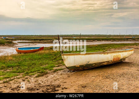 Kleine traditionelle hölzerne Fischerboote auf Wattflächen mit Blick auf die Salzwiese Am Brancaster Staithe Hafen in Norfolk Stockfoto