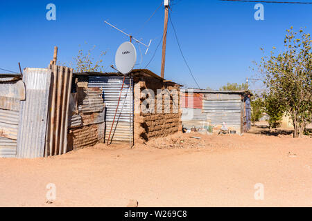 Home aus Wellblech, mit einem großen Satellitenschüssel, in einem Township in der Nähe von Otjiwarongo, Namibia Stockfoto