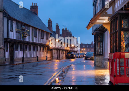 Autos geparkt entlang der Church Street in Stratford upon Avon bei Abenddämmerung eine Straße, die von traditionellen Fachwerkhäusern im Tudor-Stil gesäumt ist Stockfoto