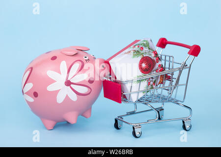 Weihnachten Geschenke in einem Supermarkt Trolley auf blauem Hintergrund mit Freiraum für Text Stockfoto