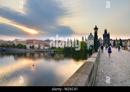 Prag, Tschechische Republik - 27. Juni 2019: Touristen zu Fuß auf der berühmten Karlsbrücke in den frühen Morgen. Sunrise Licht. Berühmte gotische Wahrzeichen und beliebte Touristenattraktion. Stockfoto