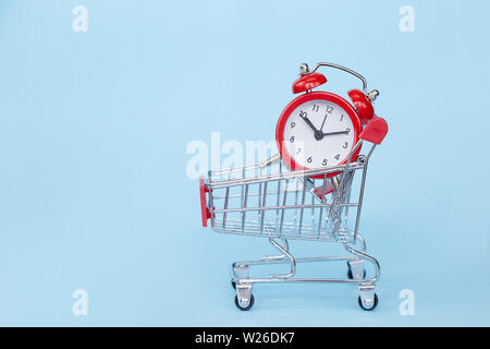 Weihnachten Geschenke und Wecker in einem Supermarkt Trolley auf blauem Hintergrund mit Freiraum für Text Stockfoto