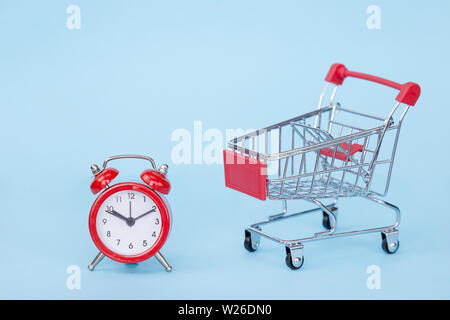 Weihnachten Geschenke und Wecker in einem Supermarkt Trolley auf blauem Hintergrund mit Freiraum für Text Stockfoto