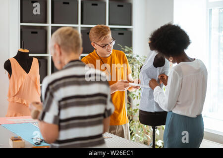 Männlicher Kollege. Rückansicht Portrait von zwei weiblichen Mode Designer gemeinsam mit ihren männlichen Kollegen in einem Studio Stockfoto