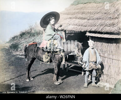 [1890s Japan - Japanische Frau auf Pferd] - Eine weibliche Reisende mit einem Sonnenschirm reitet eine ziemlich traurige Suche Pferd von einem Landwirt statt. Die strohgedeckten Gebäude erscheint eine Ruhestätte zu sein. 19 Vintage albumen Foto. Stockfoto