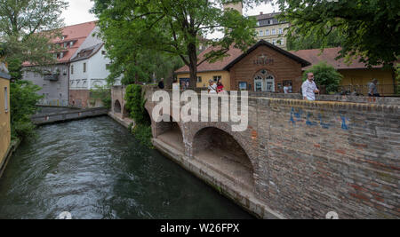 Augsburg, Deutschland. 06 Juli, 2019. Passanten Spaziergang entlang einer der Stadt strömen. Die Unesco hat die Wasserwirtschaft in Augsburg als Weltkulturerbe anerkannt. Der Ausschuß umfaßt die historische Wasserversorgung, die einst von den Römern gegründet wurde, auf der Liste des Weltkulturerbes. Quelle: Stefan Puchner/dpa Quelle: dpa Picture alliance/Alamy Live News/dpa/Alamy leben Nachrichten Stockfoto