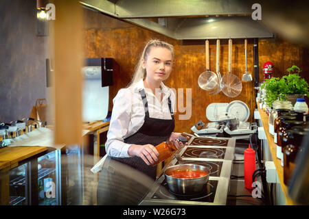 Koch hinzufügen Würzmittel für Geschmack im kochenden Topf mit Pasta Sauce im Restaurant Küche Stockfoto