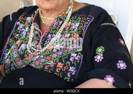 In der Nähe der alten arabischen Frau mit traditionellen arabischen Kleidung und Schmuck sitzen auf Stuhl. Stockfoto