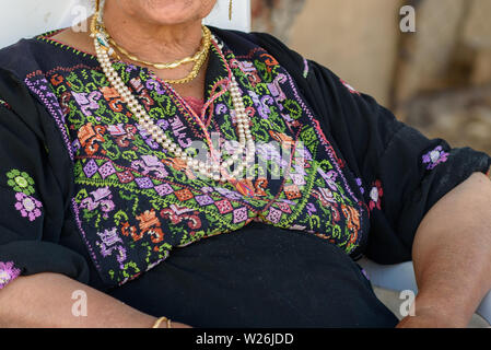 In der Nähe der alten arabischen Frau mit traditionellen arabischen Kleidung und Schmuck sitzen auf Stuhl. Stockfoto