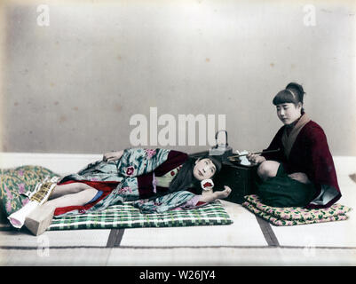 [1890s Japan - Japanische Frau Schlafen] - ein Frauen liegt auf einem Futon, während andere eine kiseru Rohr in einer Einstellung Studio hält. 19 Vintage albumen Foto. Stockfoto