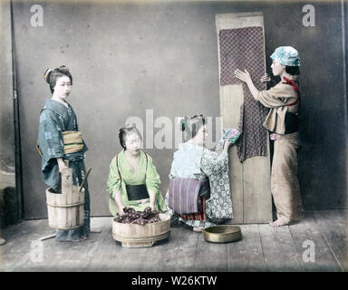 [1890s Japan - Japanische Frauen Waschen] - vier Frauen im Kimono und traditionellen Kopfbedeckungen sind die Wäsche machen. Die Frau in der Mitte ist das waschen Kleidung in einer Oke (hölzerne Schaufel), während eine Frau auf der rechten Seite ist ein Stück Textil Verbreitung auf einem Holzbrett. 19 Vintage albumen Foto. Stockfoto