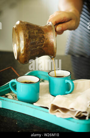 Eine Frau giesst Kaffee in einen Becher Stockfoto