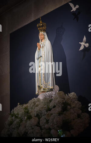 Religiöse christliche Katholische Statue der Jungfrau Maria gekrönt, gekleidet in weißem Kleid an der Wall mit blauem Hintergrund Tuch in der Kathedrale von Lissabon, Portugal. Stockfoto