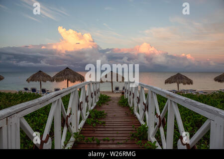 Wunderschöne Aussicht auf eine hölzerne Weg zum Sandstrand an der Karibik in Kuba bei einem bewölkten und regnerischen Morgen Sonnenaufgang. Stockfoto