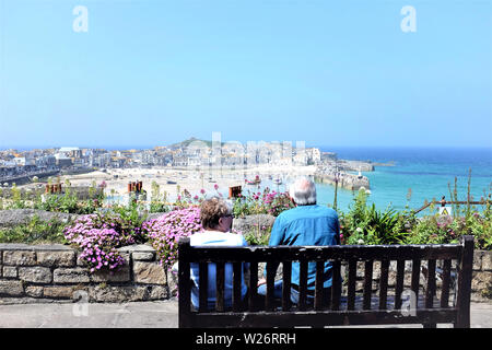 St. Ives, Cornwall, UK. Juni 26, 2019. Zwei Senioren Sitzung bewundern Sie die Aussicht auf den Hafen und die Stadt von der Malakoff Gärten in St. Ives in Co Stockfoto