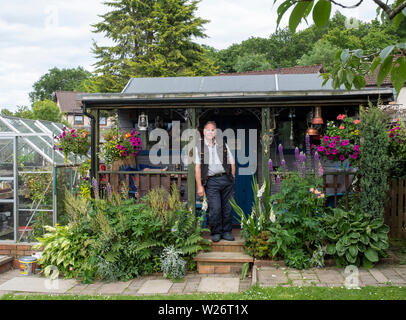 Portrait von Jim und seine Hausgemachte bothy im Garten seines Hauses. Stockfoto