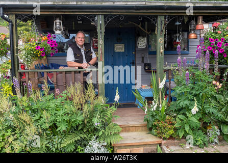 Portrait von Jim und seine Hausgemachte bothy im Garten seines Hauses. Stockfoto