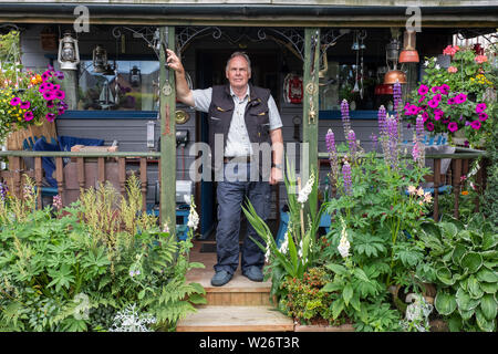 Portrait von Jim und seine Hausgemachte bothy im Garten seines Hauses. Stockfoto