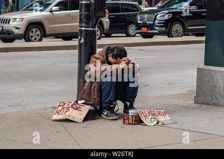 USA, Chicago, Illinois. Mai 9, 2019. Obdachlosen Mann sitzt auf der Straße und Karton Zeichen um Hilfe zu bitten, der Innenstadt Stockfoto