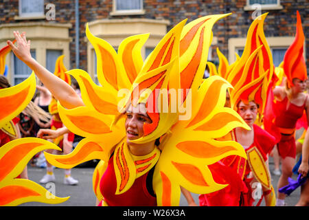 Tänzerinnen tragen bunte Flamme Kostüme in der Parade an der St Pauls Karneval, Bristol, 6. Juli 2019 Stockfoto