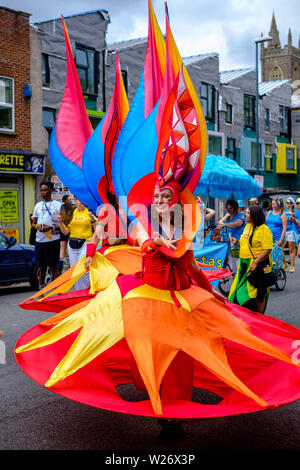 Eine Performerin tragen ein buntes, extravagantes Kostüm in der Parade an der St Pauls Karneval, Bristol, 6. Juli 2019 Stockfoto