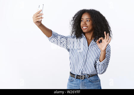 Signal okay Bild genial. Attraktive kontaktfreudig freundlich aussehende Moderne tausendjährigen dunkelhäutige Mädchen Videoanrufe Freund Hand verlängern Smar Stockfoto