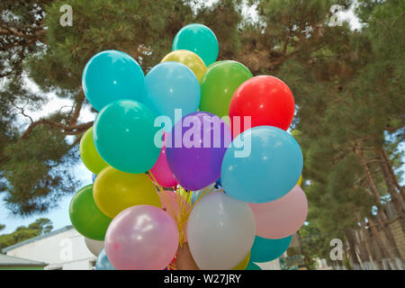 Bunte Ballone in den Himmel. Bündel von bunten Luftballons in den grünen Hintergrund. Viele bunte Luftballons für die Party im Freien Stockfoto